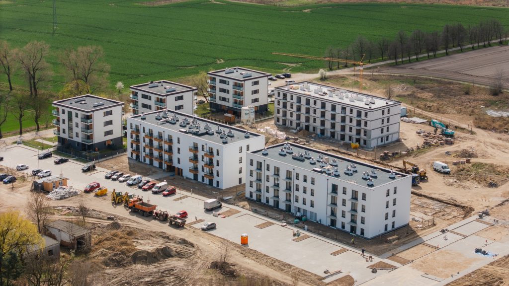 Widok z lotu ptaka na Osiedle Gwiazdowo – gotowe budynki z elewacją i zagospodarowanym terenem oraz budynki w budowie na dalszym planie.