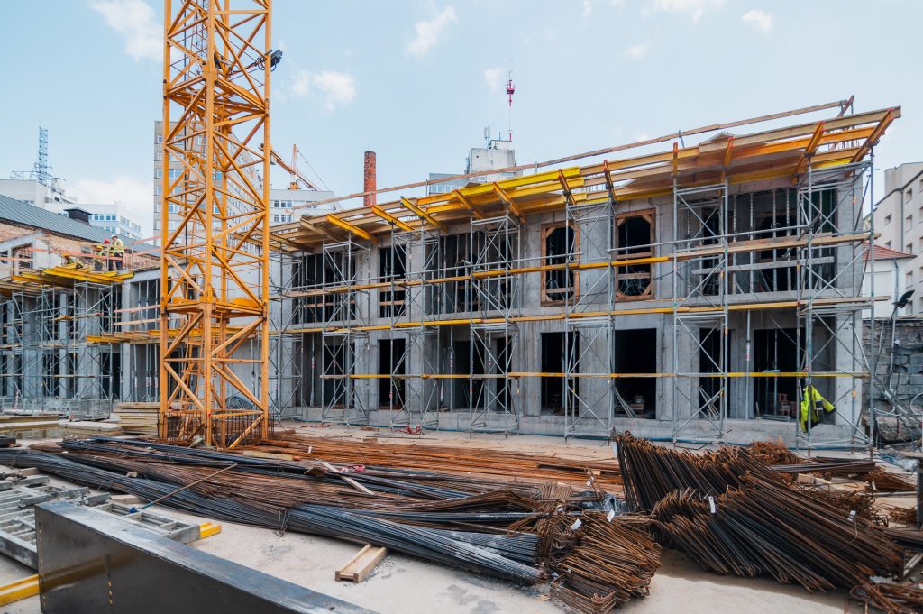 Plac budowy z rusztowaniami i zbrojeniem przygotowanym do zalania stropów w inwestycji mieszkaniowej
