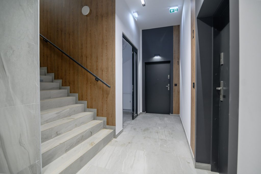 Zdjęcie wnętrza budynku A w Tarasach Rokietnicy. Widok na drzwi i klatkę schodową.