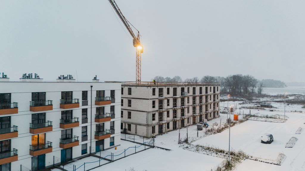 Osiedle Gwiazdowo – budynek w trakcie budowy zimą, widoczny żuraw i elewacja sąsiedniego budynku